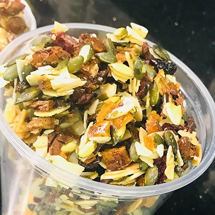 A blend of dried fruits and seeds, including pumpkin seeds, almonds, cranberries, raisins, and apricots.