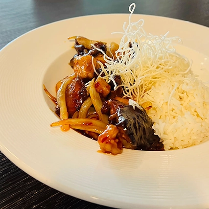 A plated dish with rice, stir-fried vegetables, and crispy noodles.