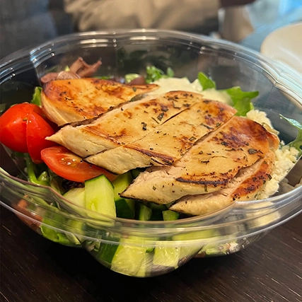 A salad with grilled chicken and fresh vegetables.
