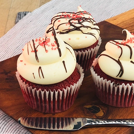 Cupcakes with frosting and decorations on a wooden board.