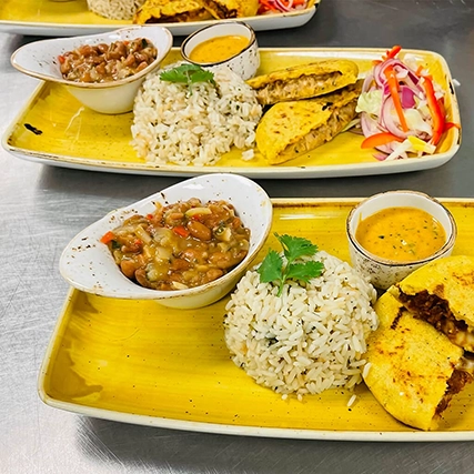 Two plates of rice, quesadillas, and various side dishes.