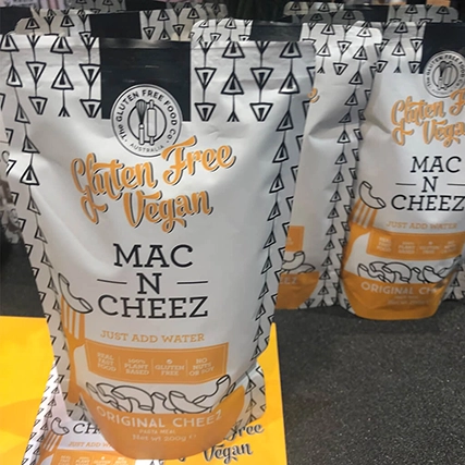 Gluten-free vegan Mac N Cheez in a stand-up pouch with bold orange lettering and a geometric design.