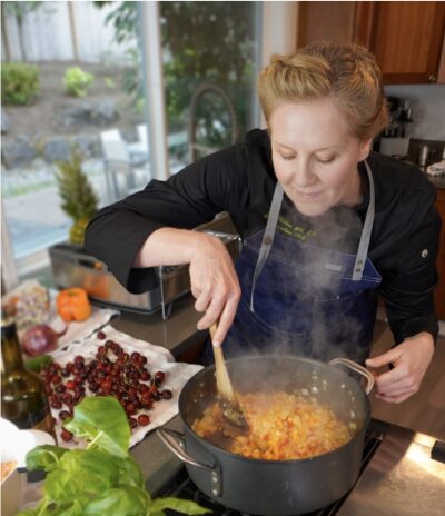 A person cooking in a modern kitchen, stirring a pot of diced vegetables