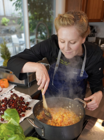 A person cooking in a modern kitchen, stirring a pot of diced vegetables